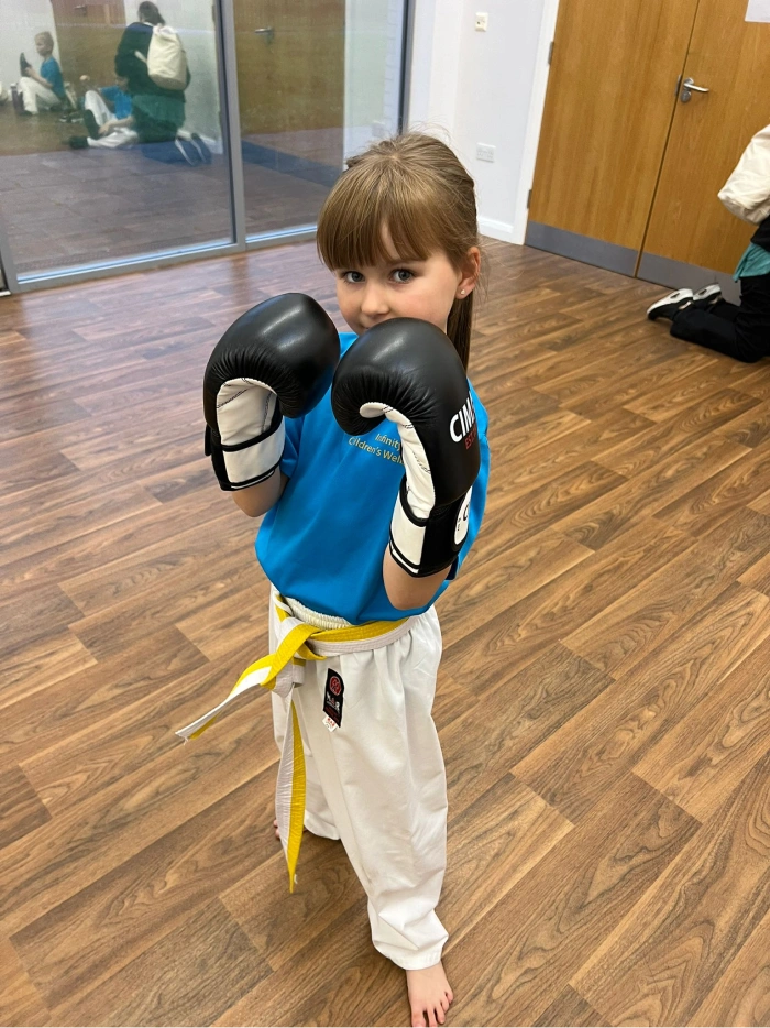 Little girl with arms up wearing boxing gloves